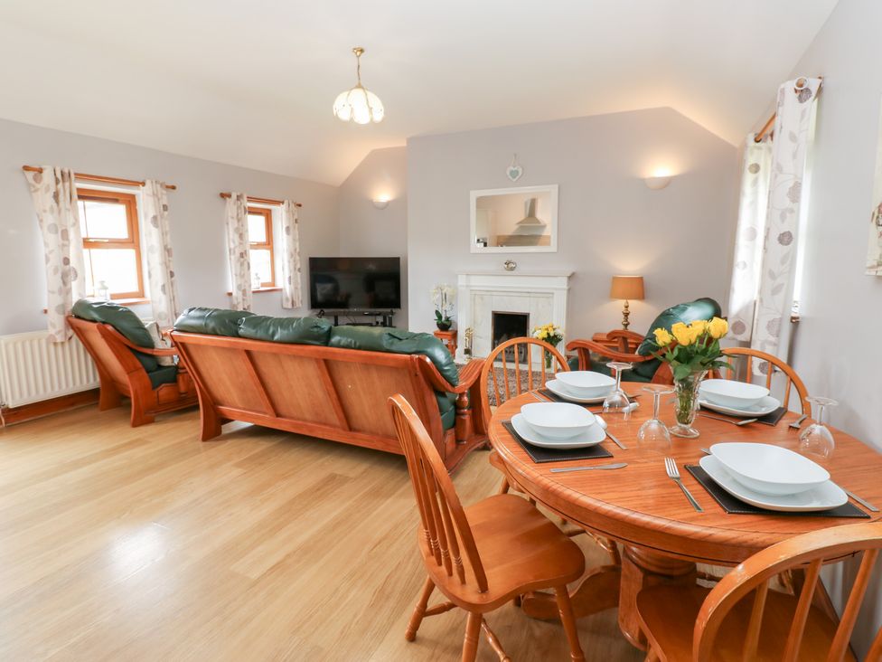 A living room with a sofa, television, and dining table at The Hayloft in Alston