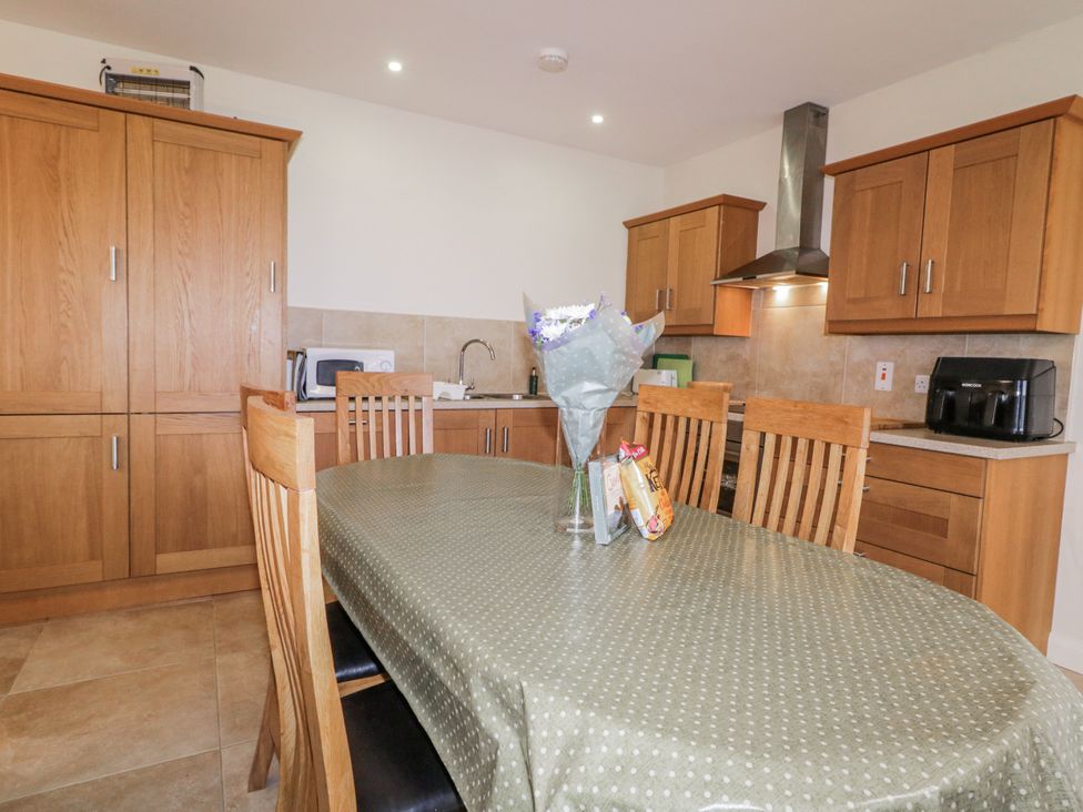 A kitchen with wood cabinets and dining table at Foyle Cottage near Strabane