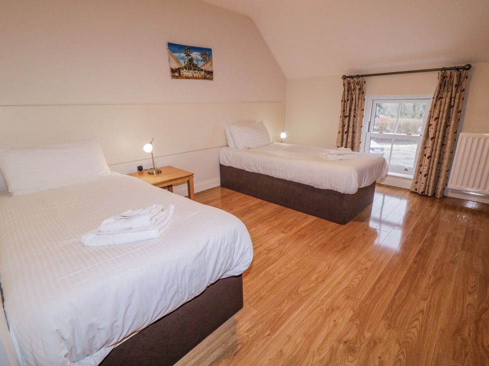 A bedroom with two beds and a table at Foyle Cottage near Strabane