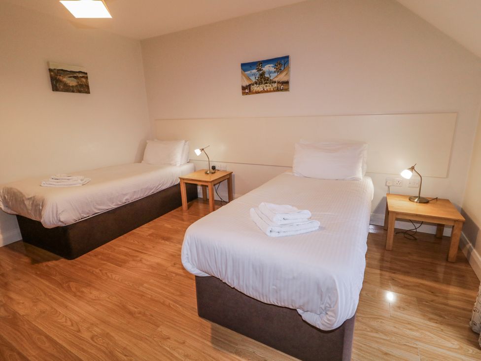 A bedroom with twin beds and a nightstand at Foyle Cottage near Strabane