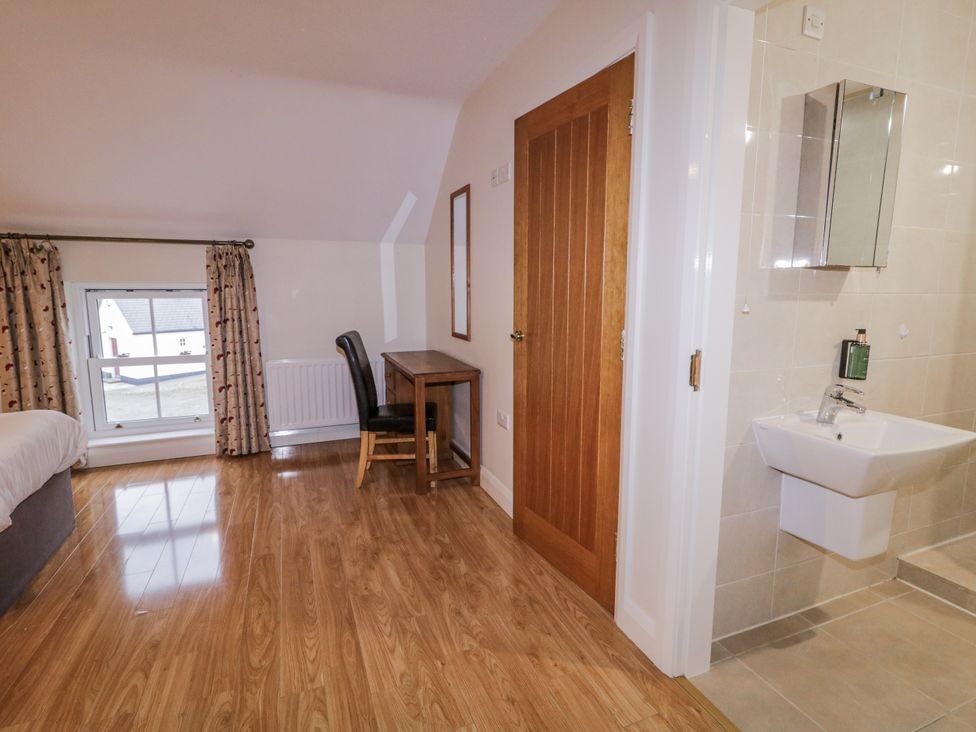 A bedroom with a bed, desk, chair, and wash basin at Foyle Cottage near Strabane