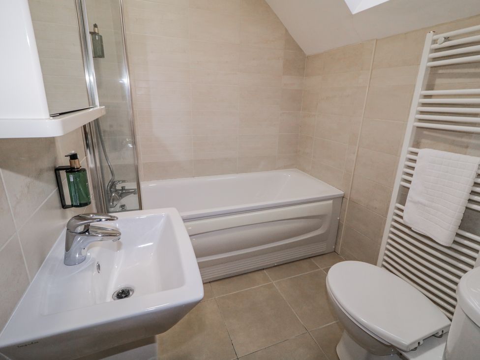 A bathroom with a bathtub, sink, and toilet at Foyle Cottage near Strabane