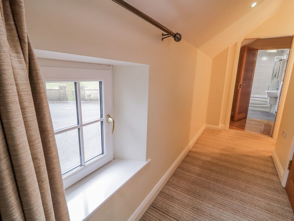 A hallway with a window and door leading to a bathroom at Foyle Cottage near Strabane