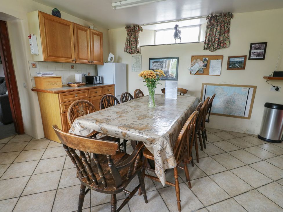 A kitchen with a dining table and cabinets at Glan y Gors in Dinorwic near Llanberis