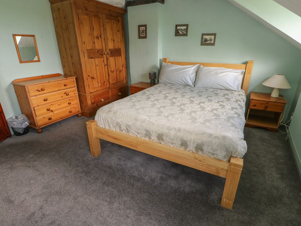 A bedroom with a bed, wardrobe, and dresser at Glan y Gors in Dinorwic near Llanberis