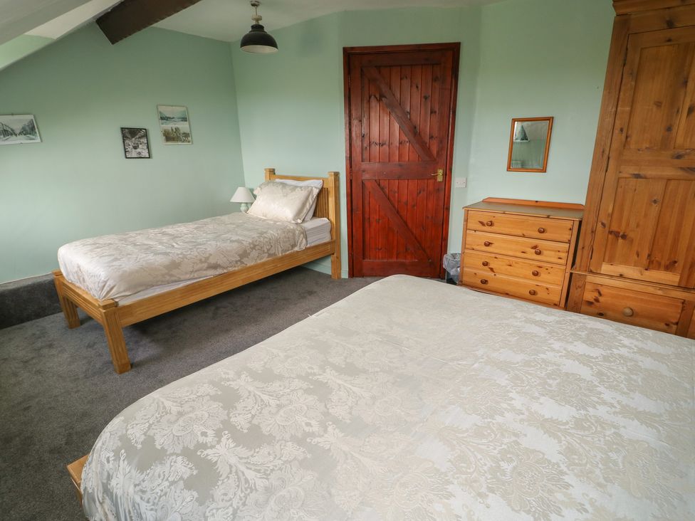 A bedroom with two beds and wooden furniture at Glan y Gors in Dinorwic near Llanberis