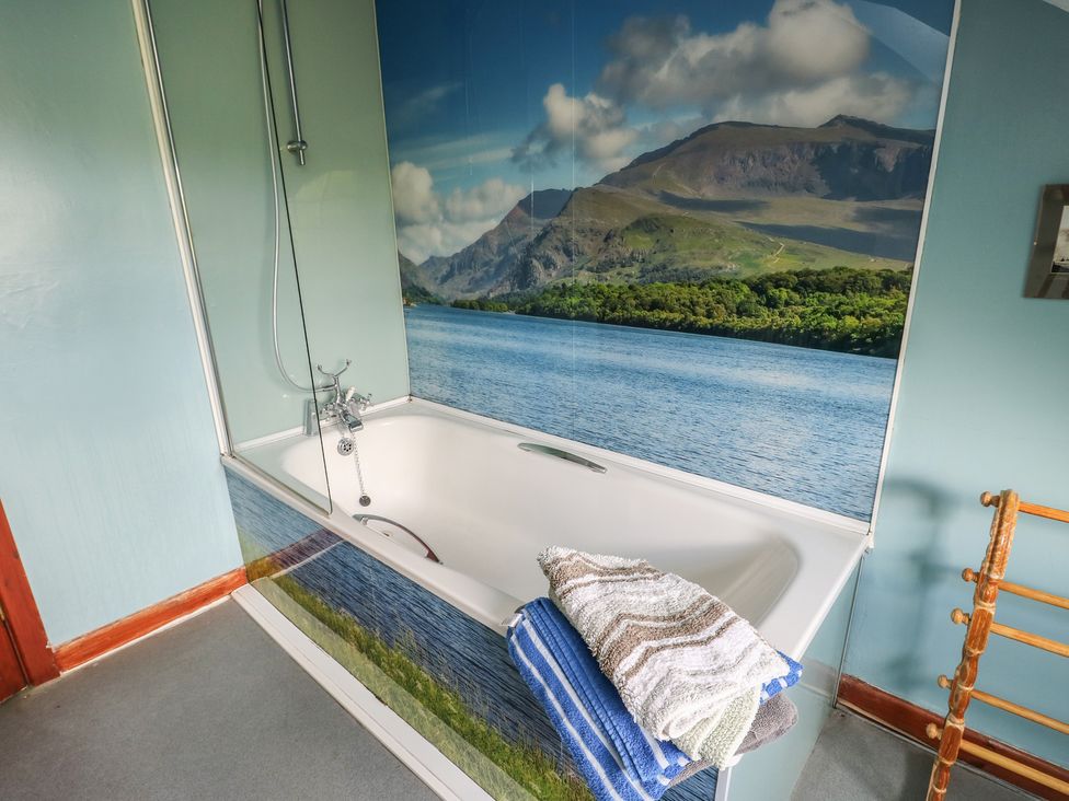A bathroom with a bathtub and towels at Glan y Gors in Dinorwic near Llanberis