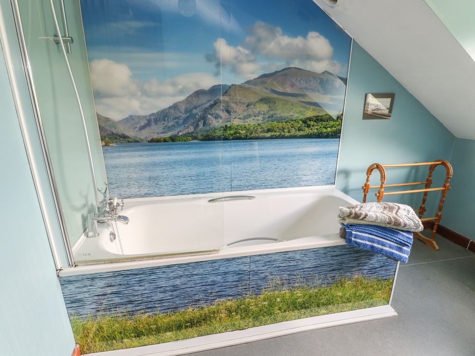A bathroom with a bathtub and a waterfall mural at Glan y Gors in Dinorwic near Llanberis