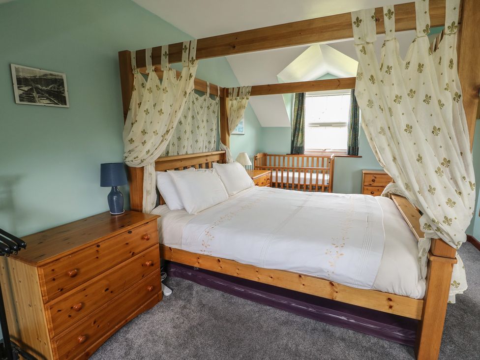 A bedroom featuring a four-poster bed and a baby crib at Glan y Gors in Dinorwic near Llanberis