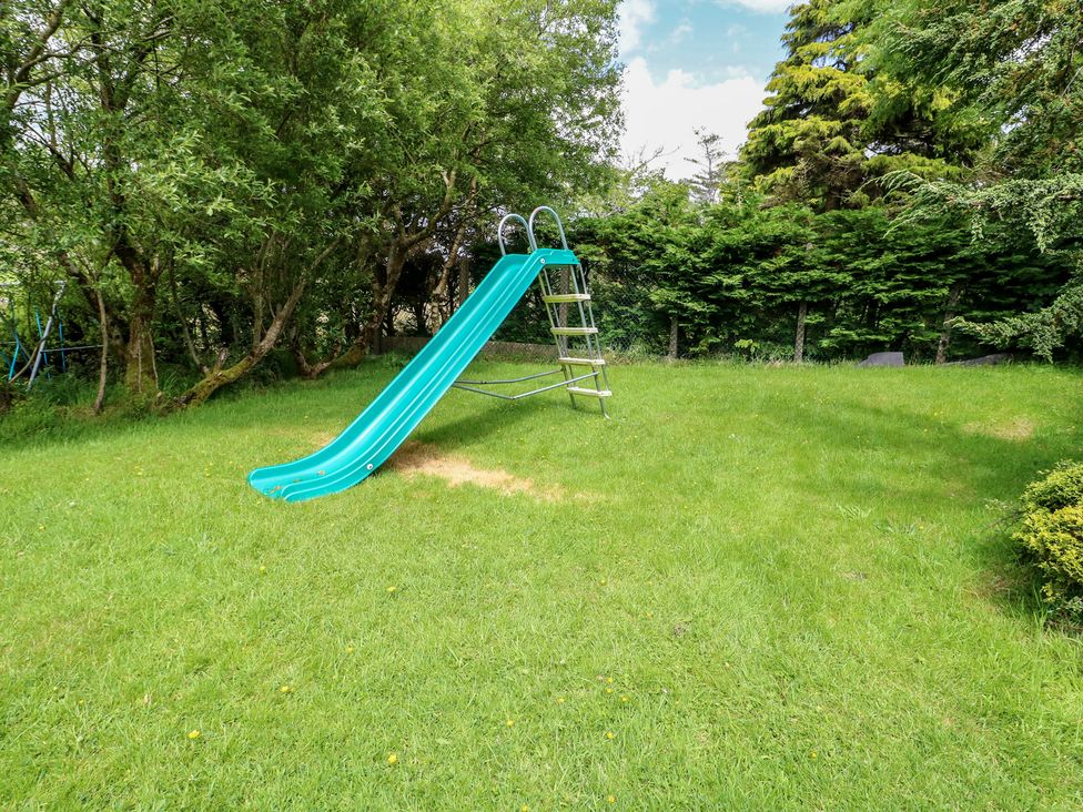 A slide in a garden surrounded by grass and trees at Glan y Gors Dinorwic near Llanberis