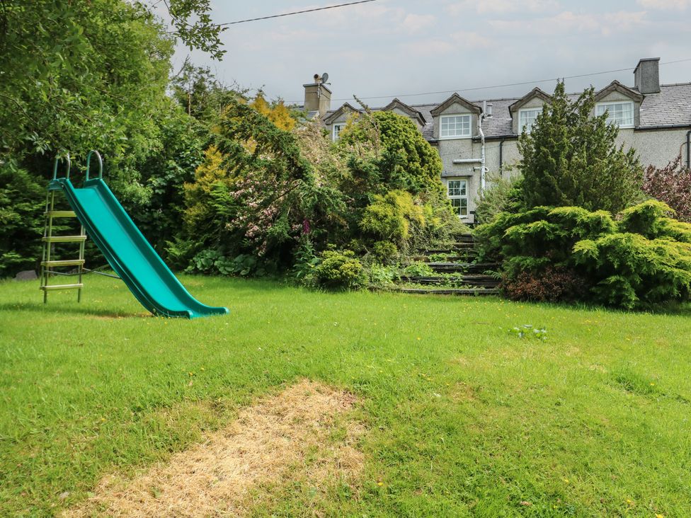 A garden with a slide and steps leading to the house at Glan y Gors in Dinorwic near Llanberis
