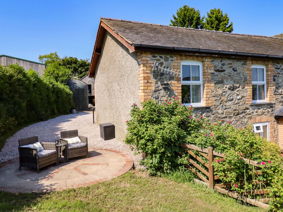 An outdoor seating area with chairs and a table near a stone wall at Peniarth in Penybontfawr near Oswestry