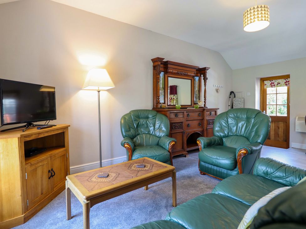 A living room with green furniture and a television at Peniarth in Penybontfawr near Oswestry