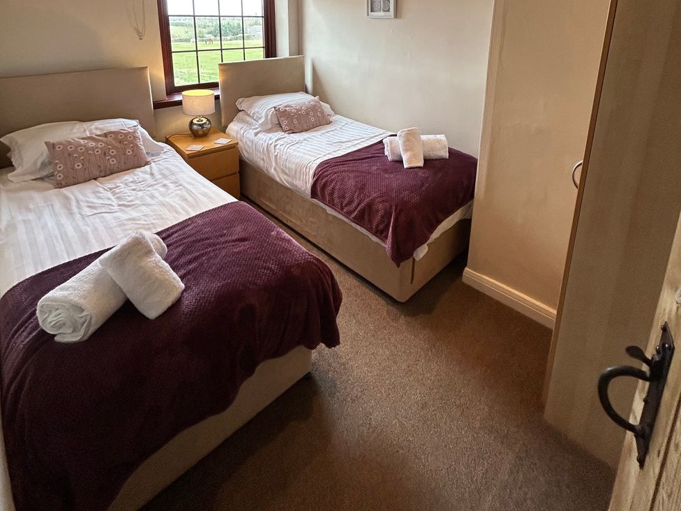 A bedroom with two beds and a bedside table at Sea Lily near Holy Island