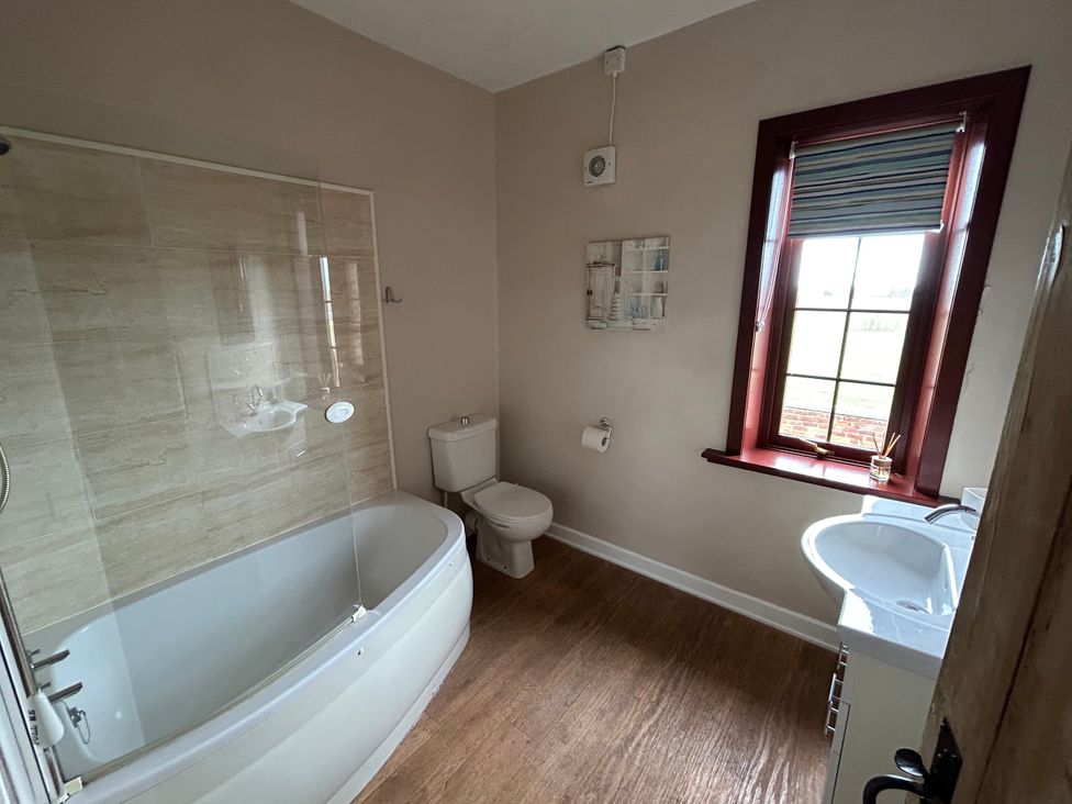 A bathroom with a bathtub, toilet, and sink at Sea Lily New Haggerston near Holy Island