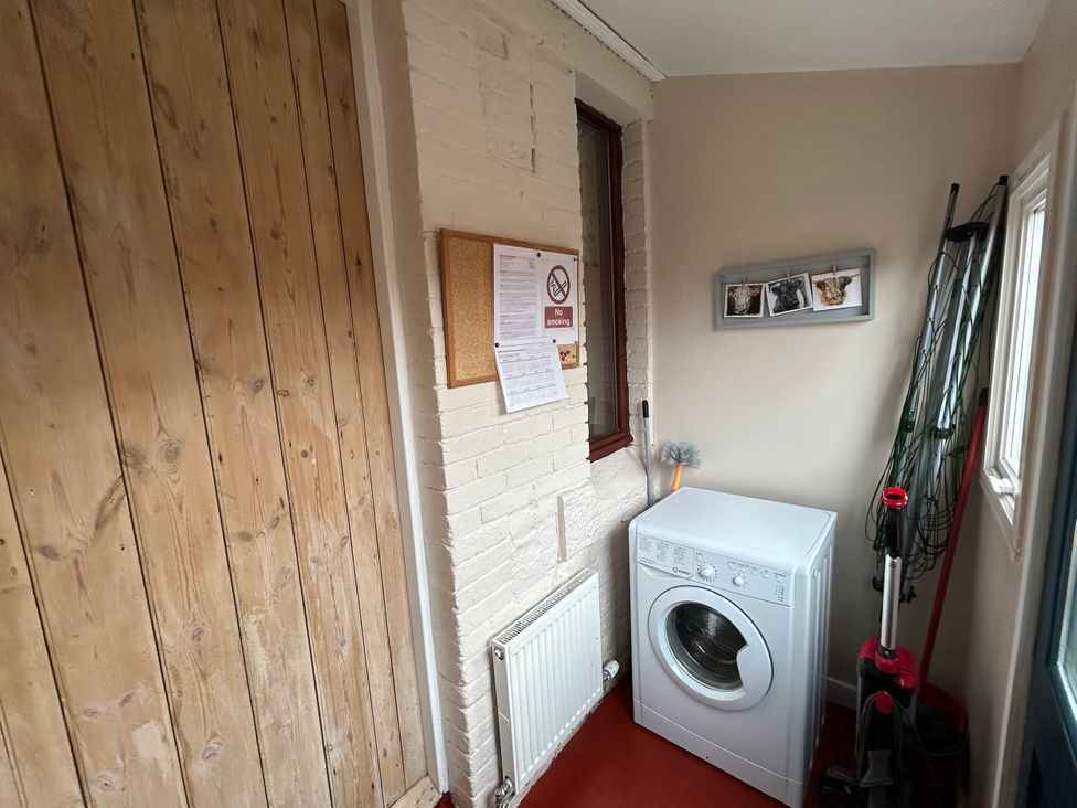 A utility room with a washing machine and corkboard at Sea Lily in New Haggerston near Holy Island