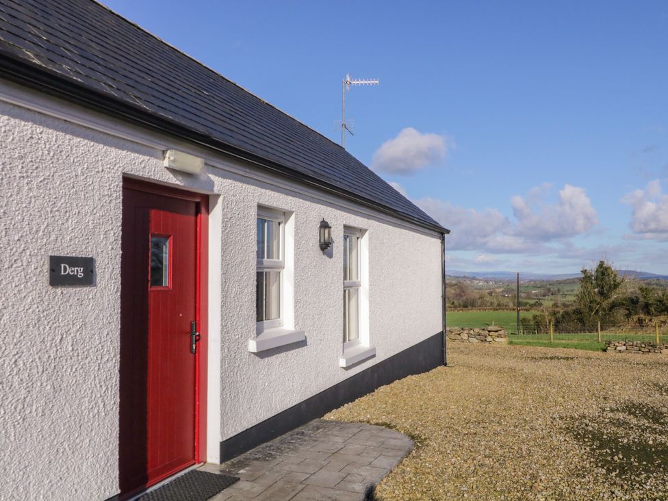 Exterior view of a white cottage with red door at Derg Cottage in 
