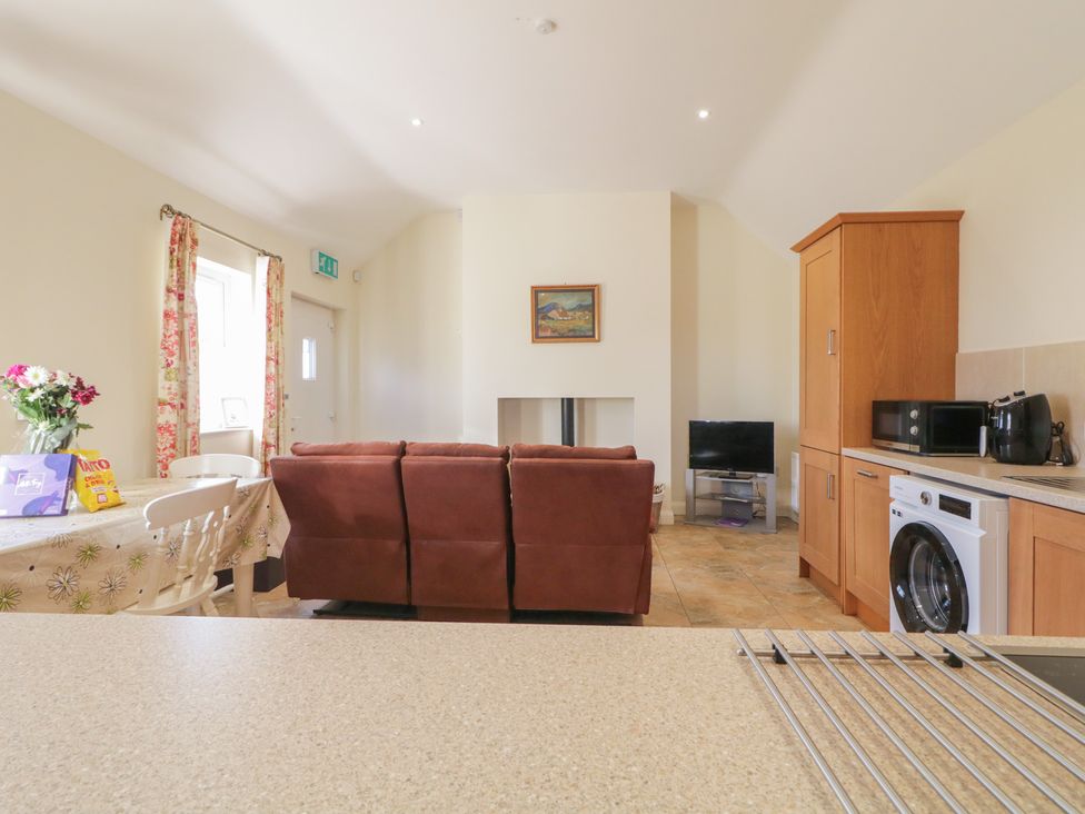 A living room with a sofa and kitchen appliances at Derg Cottage