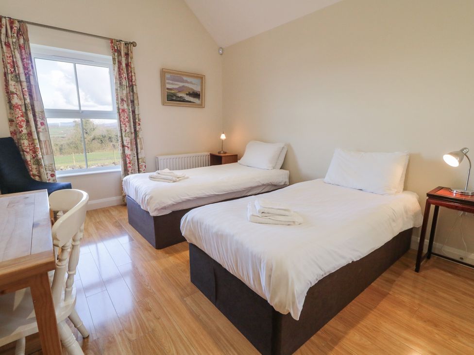 A bedroom with two single beds and a table at Derg Cottage