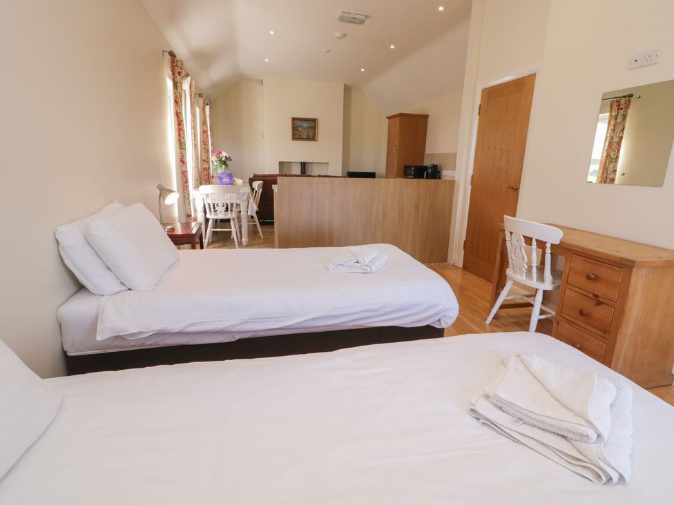 A bedroom with two beds and a table at Derg Cottage