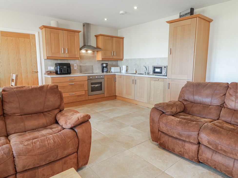 A kitchen with wood cabinets and seating area at Finn Cottage