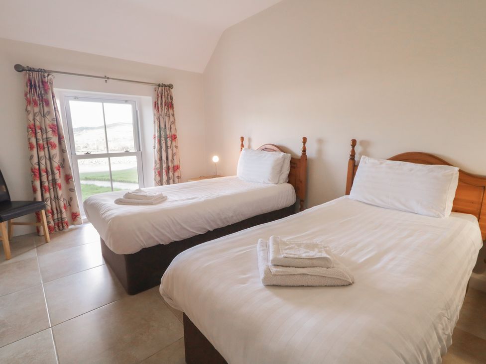 A bedroom with two beds and a window at Finn Cottage