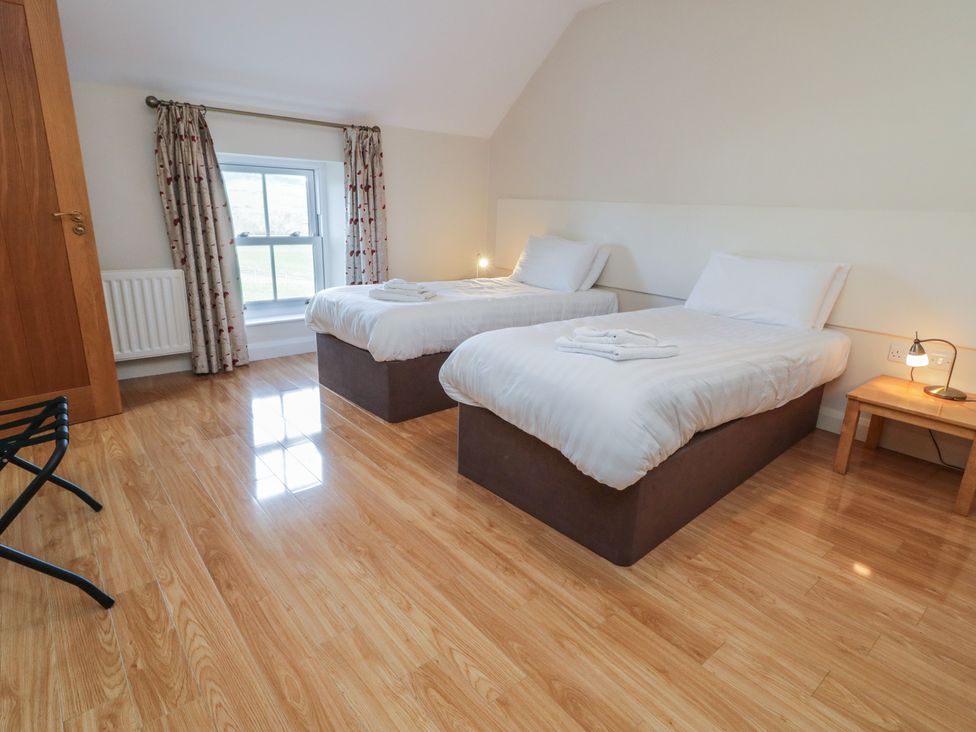 A bedroom with two single beds and a window at Finn Cottage in 