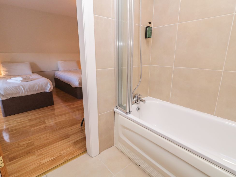 A bathroom featuring a bathtub and a doorway leading to a bedroom at Finn Cottage