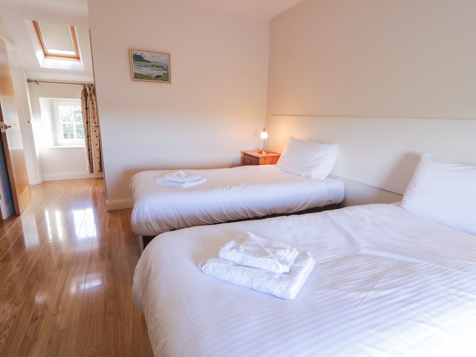 A bedroom with two single beds and a bedside table at Finn Cottage