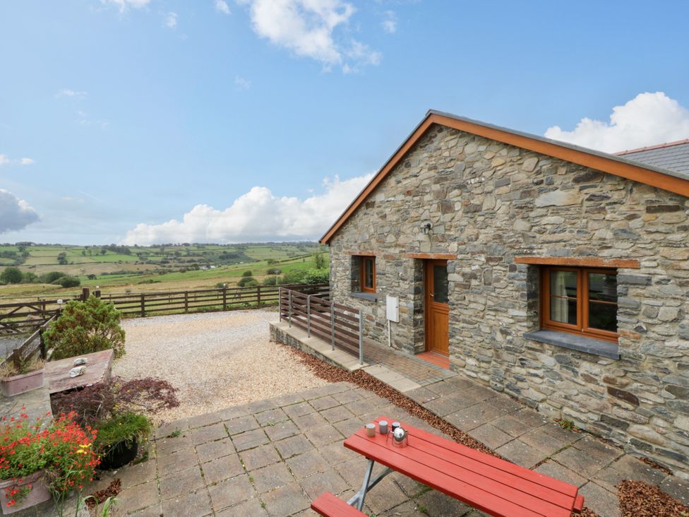An outdoor area with a stone house and seating at Y Bwthyn near Swyddffynnon near Pontrhydfendigaid