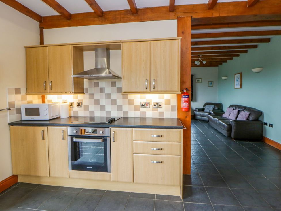 A kitchen with a stove and microwave adjacent to a living area at Y Bwthyn in Swyddffynnon near Pontrhydfendigaid