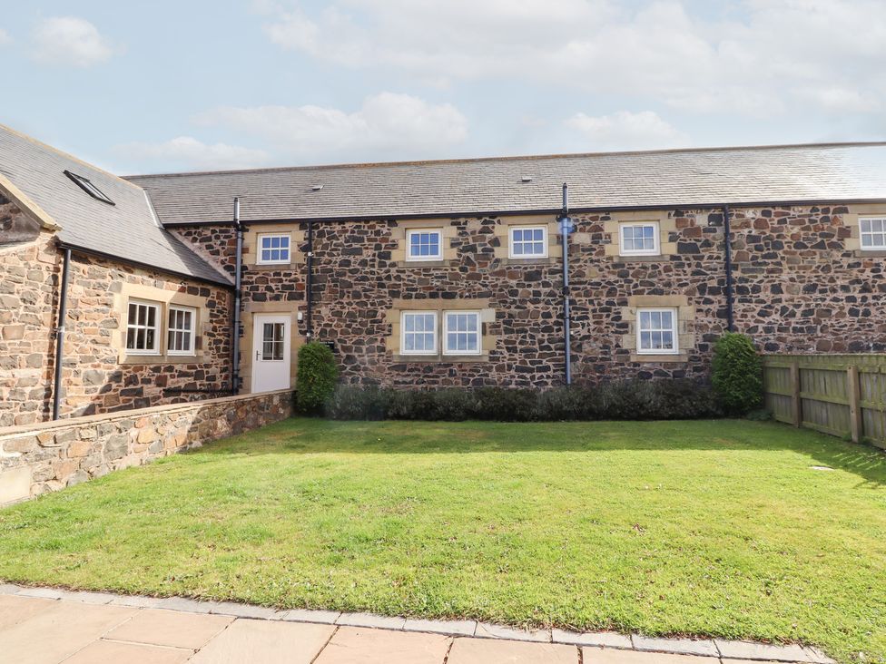 An outdoor view of a stone house with a garden at Granary Stone House Embleton