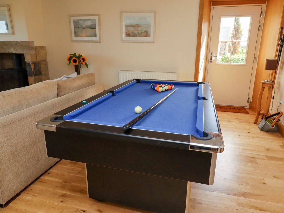 A pool table with cue stick and balls in a snug at Granary Stone House in Embleton