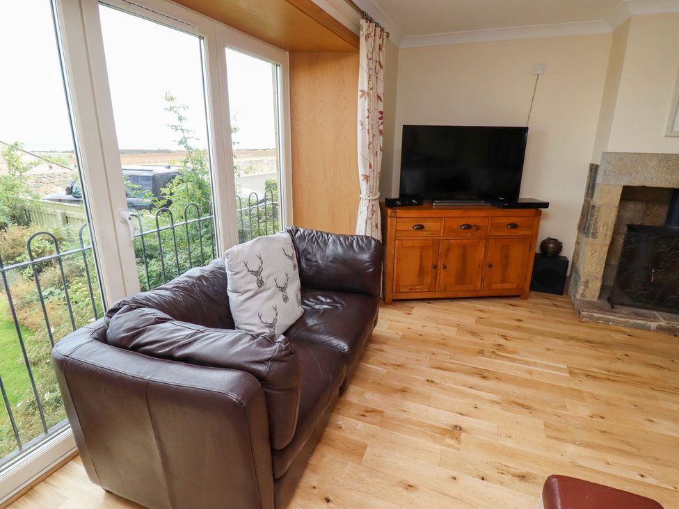A living room with a sofa and television at Granary Stone House in Embleton