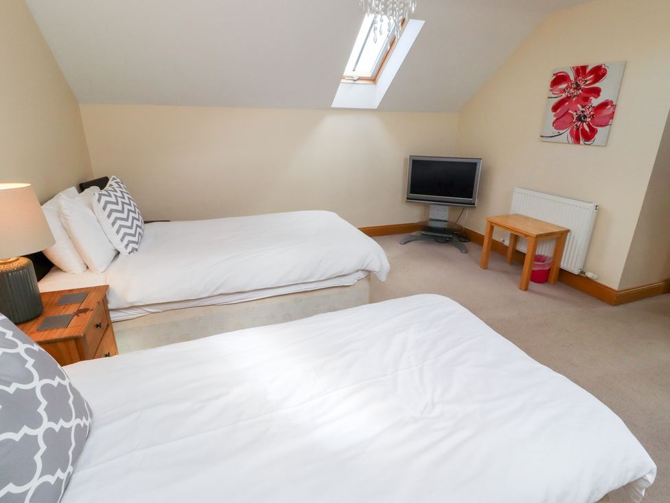 A bedroom with two beds and a television at Granary Stone House in Embleton