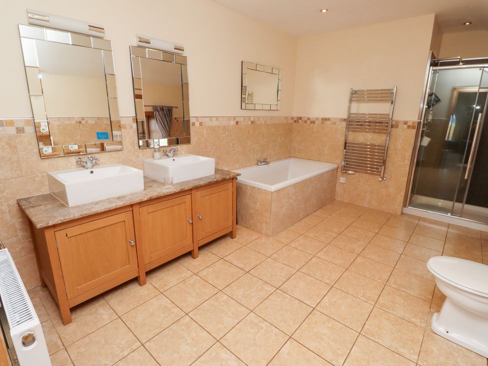 A bathroom with two sinks, a bath and a shower at Granary Stone House in Embleton
