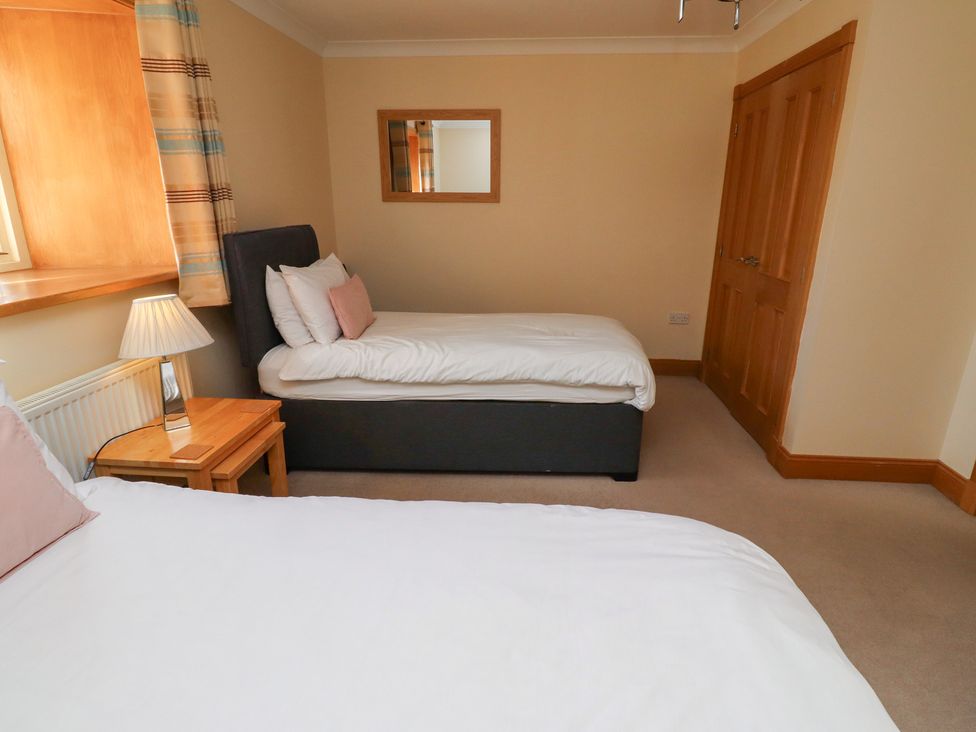 A bedroom with two beds and a nightstand at Granary Stone House in Embleton