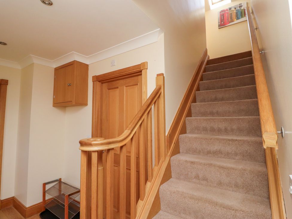A staircase with wooden handrail in a hallway at Granary Stone House in Embleton