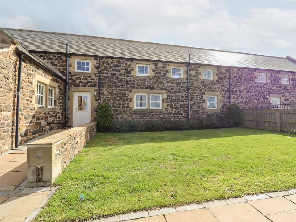 A stone building with windows and a door in a garden at Granary Stone House in Embleton