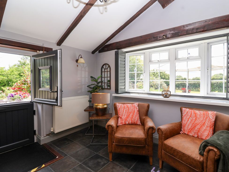 A room with two armchairs and a table at Pear Tree Cottage Mark near Burnham-on-Sea