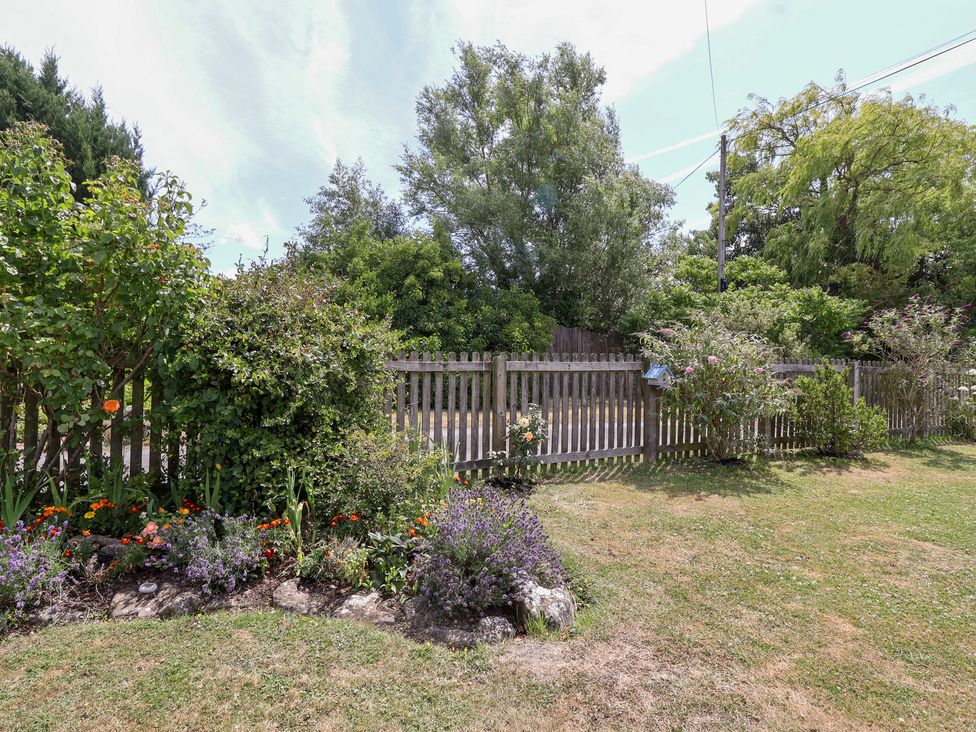 A garden with a fence and flowers at Pear Tree Cottage Mark near Burnham-on-Sea