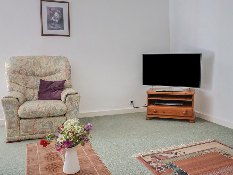 A living room with an armchair and a television at West Bowden Farm in Knowstone near South Molton