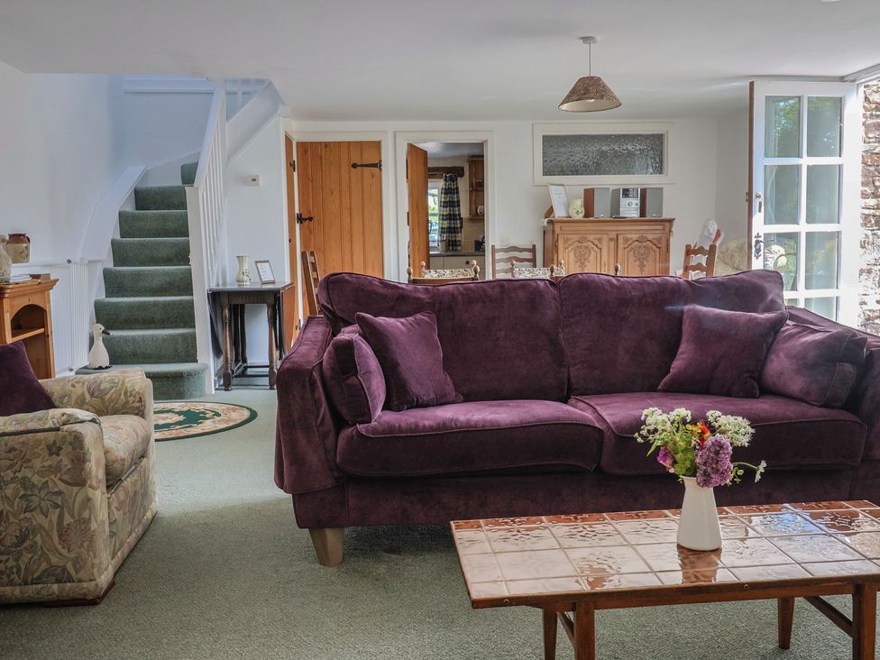 A living room with a sofa, armchair, coffee table and flowers in a vase at West Bowden Farm near South Molton