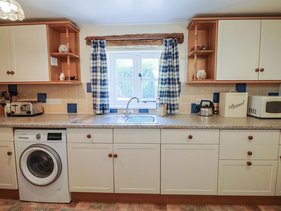 A kitchen with a washing machine and sink at West Bowden Farm in Knowstone near South Molton