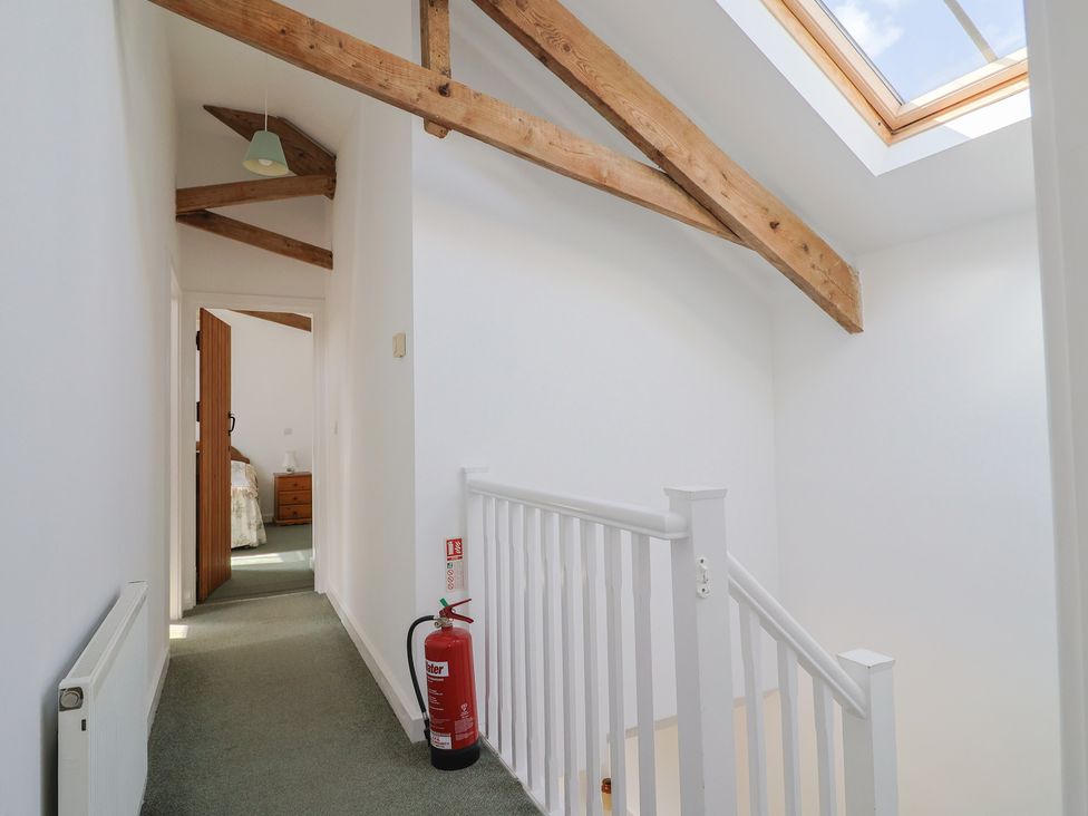 A hallway with a staircase and door to a bedroom at West Bowden Farm in Knowstone near South Molton