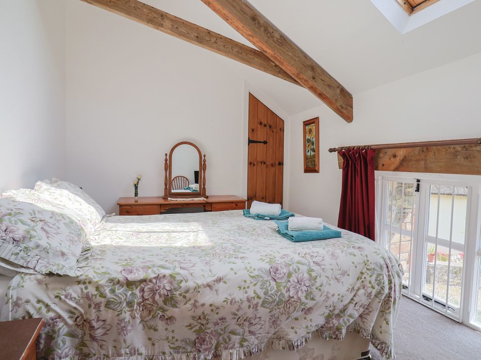 A bedroom with a bed, vanity mirror, and dresser at West Bowden Farm in Knowstone near South Molton