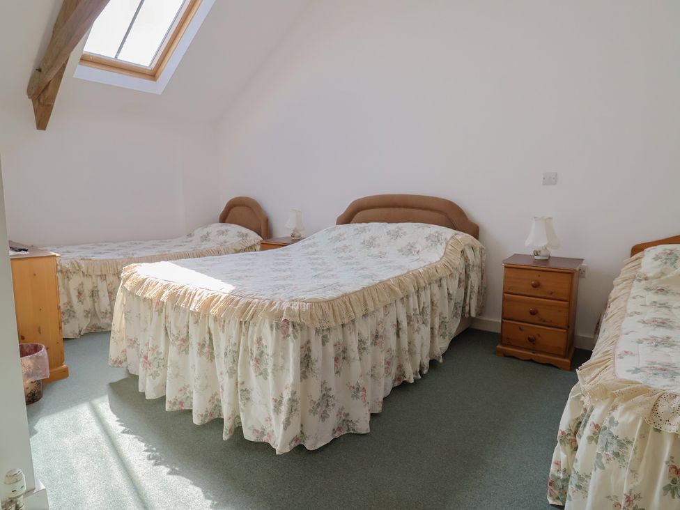 A bedroom with three beds and a window at West Bowden Farm in Knowstone near South Molton