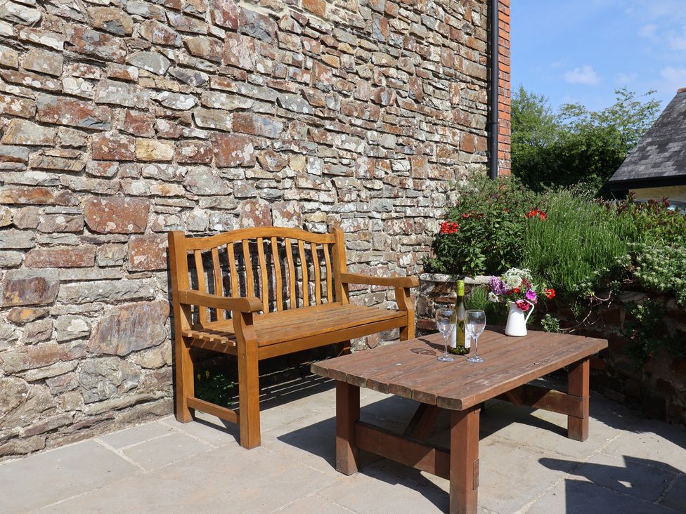 An outdoor seating area with a bench and table at West Bowden Farm in Knowstone near South Molton