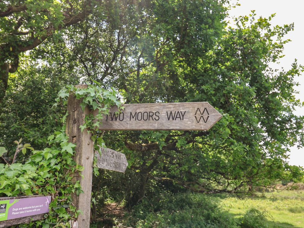 A wooden signpost for Two Moors Way in a wooded area at West Bowden Farm Knowstone near South Molton