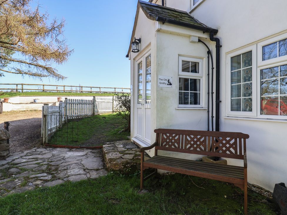 An outdoor view with a bench and entrance at The Old Smithy Dottery near Bridport